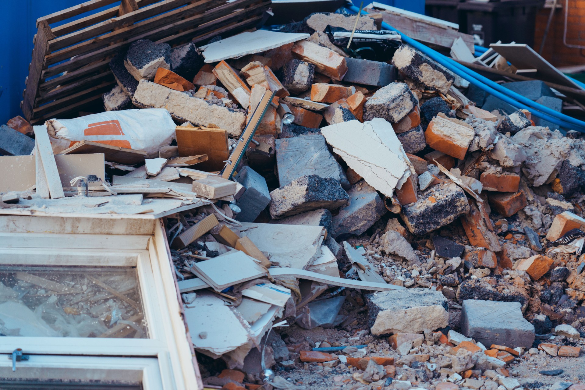 A pile of construction waste near private house. Building rubble, bricks, stones. Junk, garbage piled up near the building. Street scene. Recycling industry, rubbish removal and collection service.