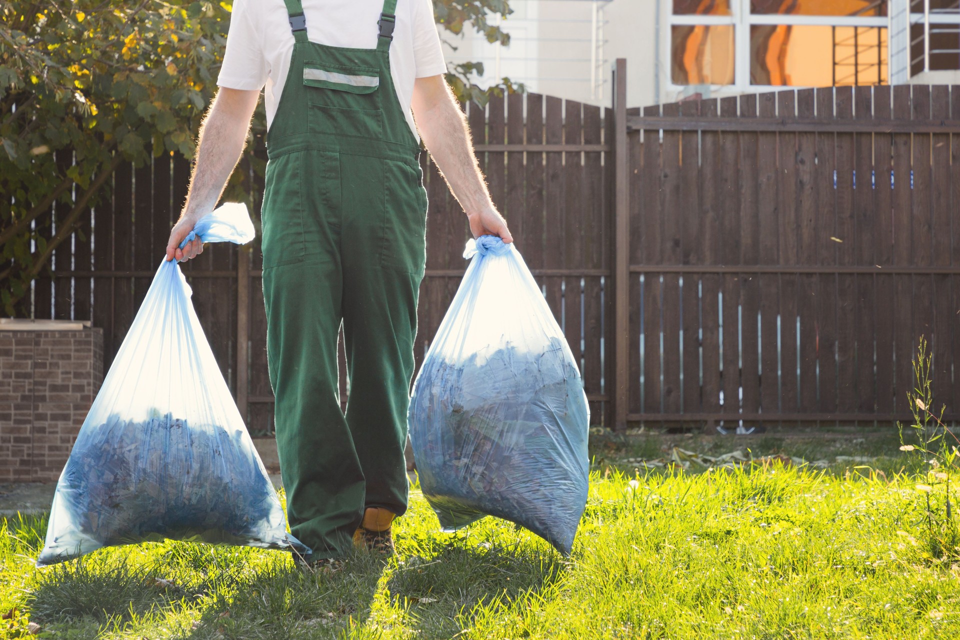 The gardener removes the bags of leaves. Light. Green uniform